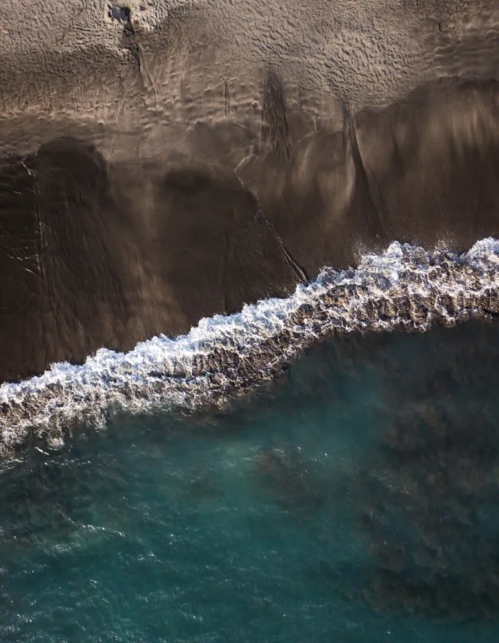 Schwarzer Vulkansandstrand mit türkisgrünen Wellen an der Küste Teneriffas